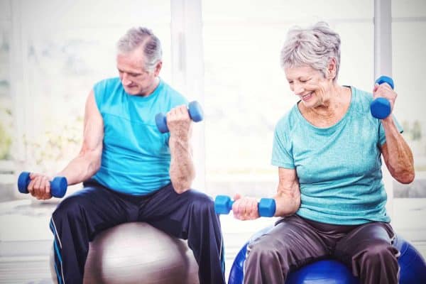 Elderly couple doing seated arm exercises with dumbbells in Riverside Township.