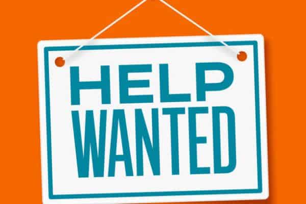 Help wanted sign hanging on orange background for job opportunities in Riverside Township.