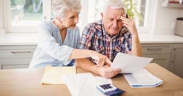 Elderly couple reviewing documents for tax deferral program.