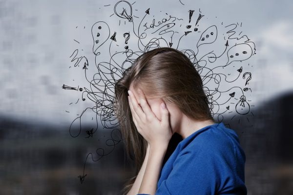 Teen girl with head in hands, surrounded by confusing question marks and symbols.